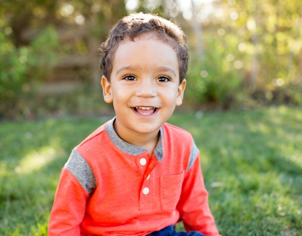 Cute Little Boy Sitting In The Grass Outside