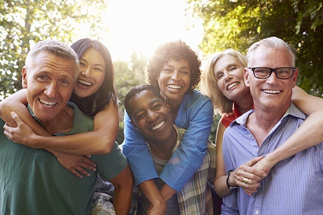 Mature Friends Giving Piggybacks In Backyard Together