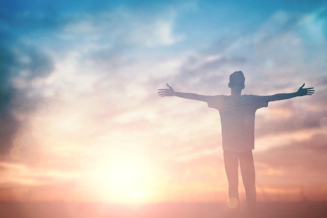 Silhouette Of Man With Raised Hands Over Blur Cross Concept For Religion, Worship, Prayer And Praise.