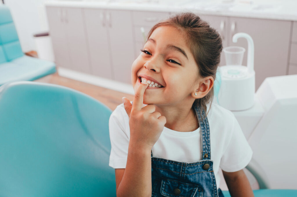 girl showing her perfect toothy smile while sitting dentists chair