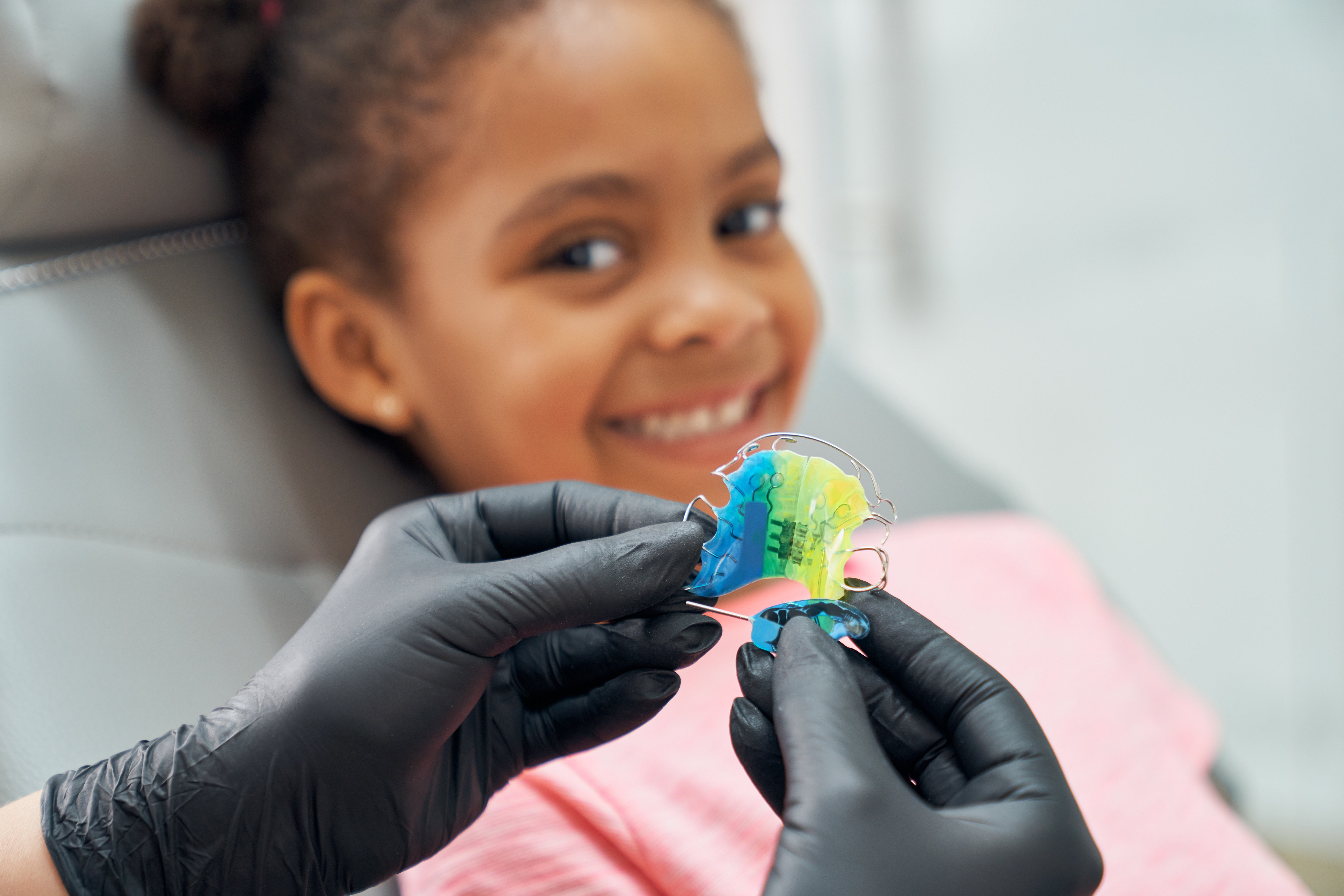 dentist presenting retainer to little girl
